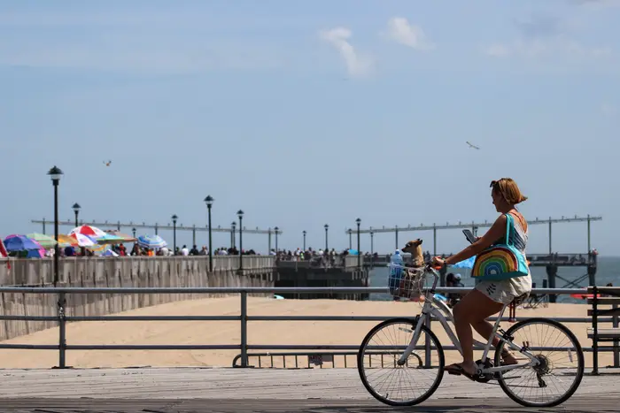 A photo of a woman riding a bike on the Coney Island Boardwalk